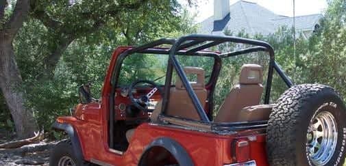The rear three-quarter of a red 1978 Jeep CJ5 showing the spare tire mounted on the back, the roll bar and the open body