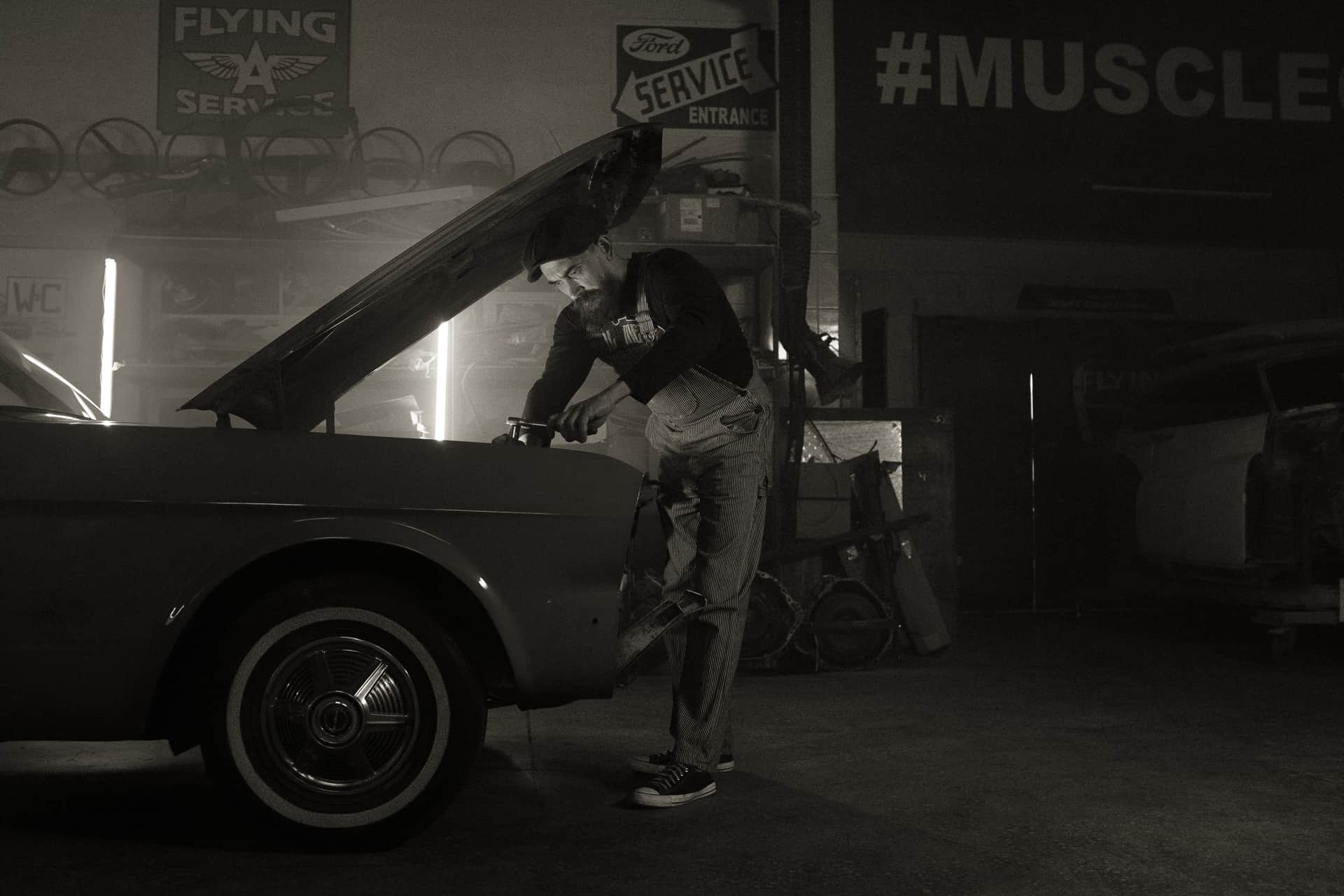 A classic Ford with the hood up in a home garage workshop