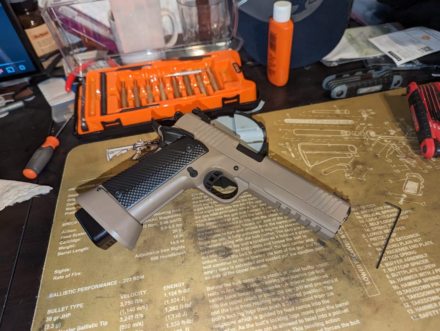 The refinished pistol in tan with a gray slide, partially reassembled on the bench mat